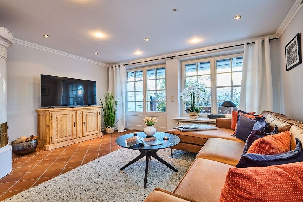 Un salon avec un canapé, une table basse, un téléviseur et une fenêtre avec des rideaux.