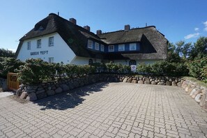 A traditional building with a thatched roof and a sign reading 'GREEN PEAR TREE.' - Luxury suite "Beach Style" under a thatched roof (Keitum)