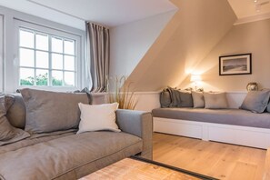 A modern living room with a sofa and a smaller seating area, large windows, and a lamp. - Luxury suite "Beach Style" under a thatched roof (Keitum)