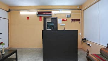 A hotel lobby with a reception desk, a clock, and a 'no smoking' sign.