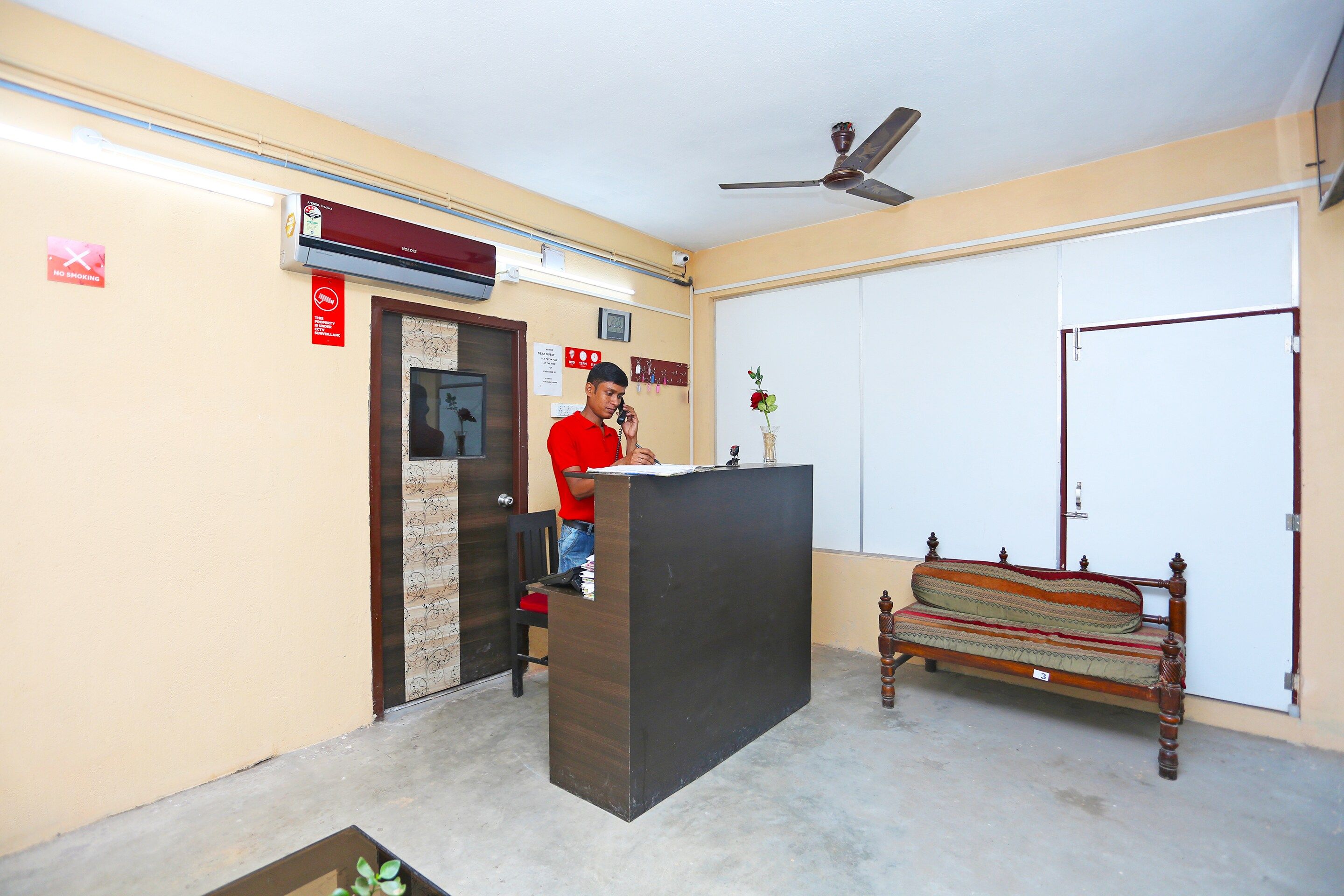 A reception area with a desk, a bench, a ceiling fan, and a closed door.
