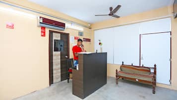A reception area with a desk, a bench, a ceiling fan, and a closed door.