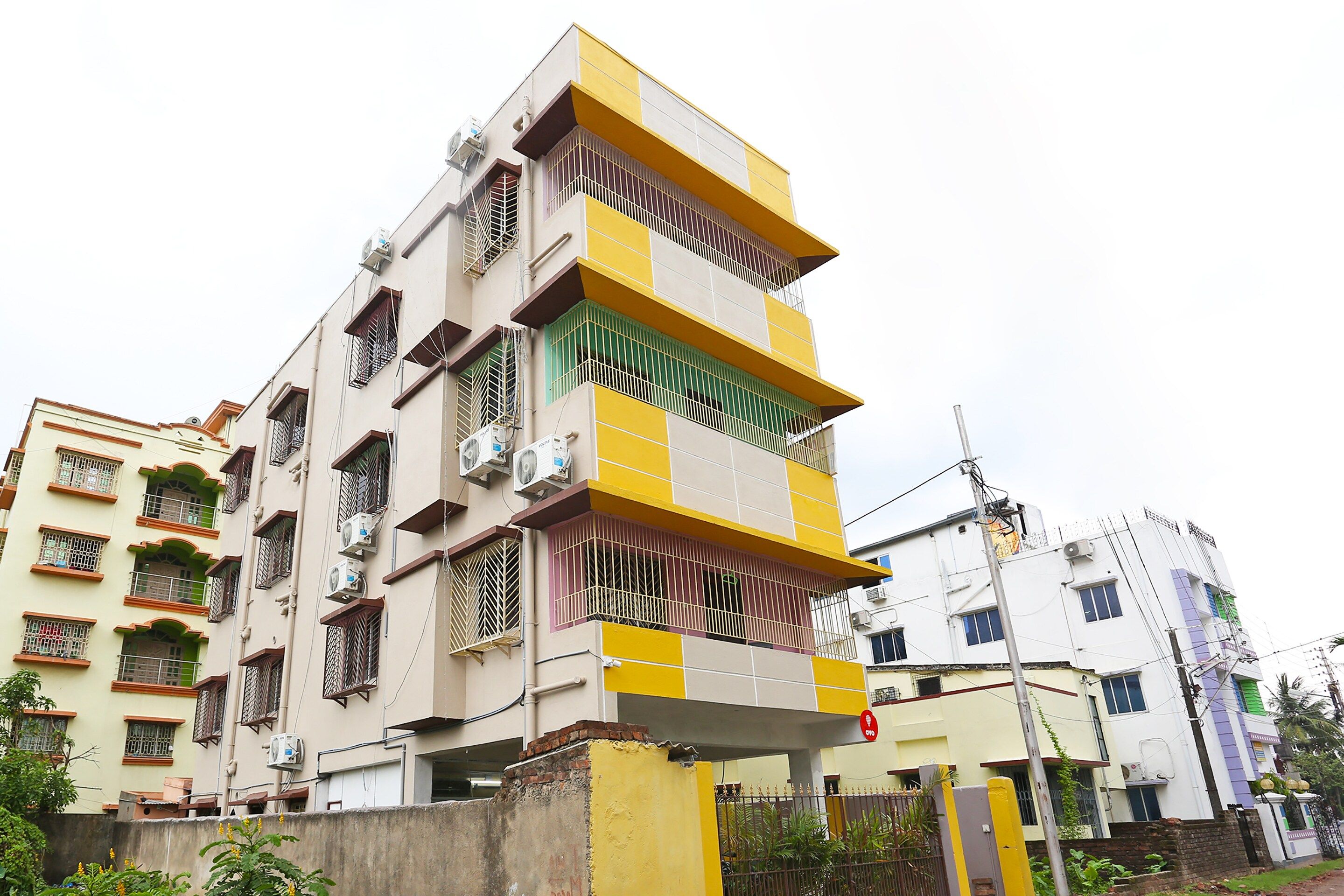 A multi-story residential building with balconies, air conditioning units, and a gated entrance.