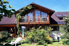 A two-story house with a balcony, surrounded by greenery and a garden. - Holiday apartment with 1 bedroom (Meersburg)