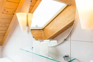 A bathroom with a skylight, a glass shelf with toiletries, and a wooden ceiling. - Holiday apartment with 1 bedroom (Meersburg)