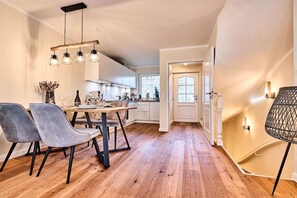 A modern kitchen with a dining area, wooden flooring, and a staircase leading to another level. - Holiday home with 3 bedrooms (Westerland)