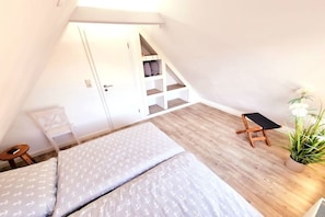 A bedroom with a lofted sleeping area, a small table, and a potted plant. - Holiday home in Zingst with swimming pool (Zingst)