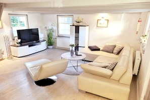 A modern living room with a sofa, two armchairs, a coffee table, a TV, and a potted plant. - Holiday home in Zingst with swimming pool (Zingst)
