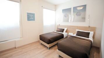 Ein Hotelzimmer mit zwei Betten, einem Fenster mit Jalousien, einem Wandbild und einem Schild mit dem Text 'LESS IS MORE'.