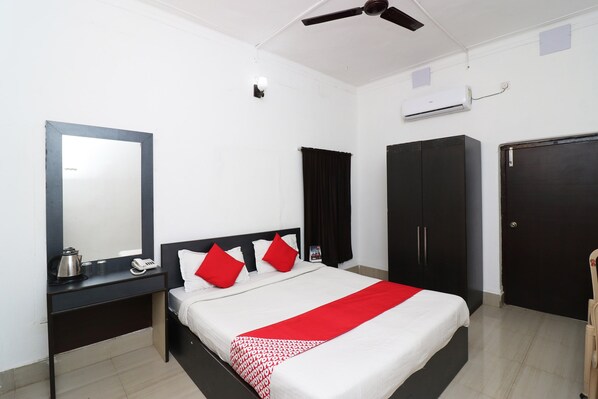 A hotel room with a bed, a bedside table with a phone and a kettle, a wardrobe, a mirror, and a ceiling fan. - Hotel O Jalan Lake View Near Mani Square (Kolkata)