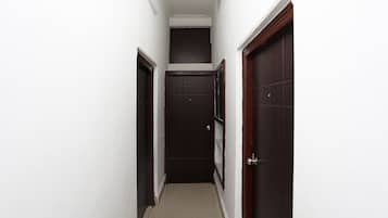 A narrow hallway with white walls and dark wooden doors.