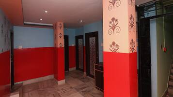 Un pasillo con paredes rojas y azules, suelo de mármol y columnas decorativas.