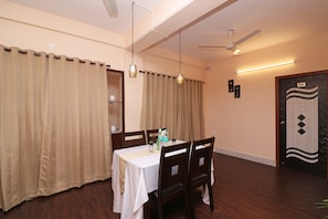 A dining area with a table set for two, a ceiling fan, and a door with a number. - Hotel O A RETRO (Barasat)