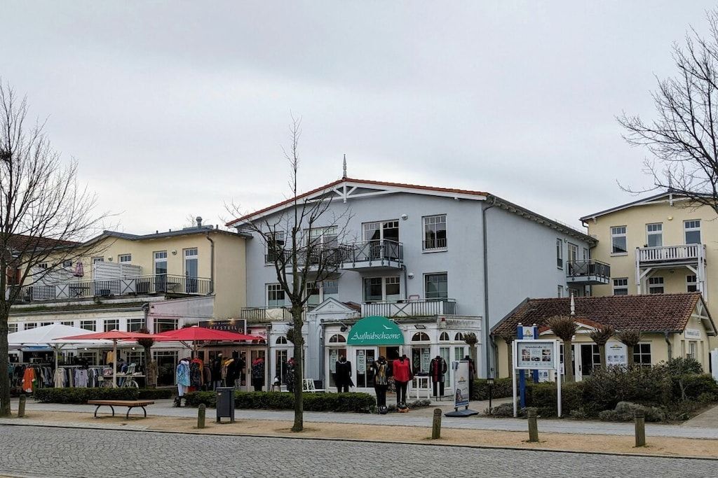 Un bâtiment sur lequel on peut lire l’inscription « Authibuschsone », ainsi qu’une rangée de boutiques dotées d’auvents rouges.