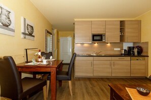 A compact kitchen with wooden cabinets, a microwave, and a coffee maker. - Holiday apartment Villa Patricia 319561 (Kühlungsborn-Ost)