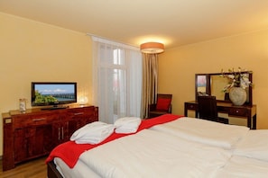 Ein Hotelzimmer mit Bett, Schreibtisch, Fernseher und einem Fenster mit Vorhängen.