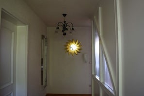 A hallway with a chandelier and a wall-mounted sunburst light fixture. - Holiday apartment with 3 bedrooms (Strullendorf, Germany)