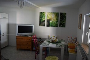 Ein kompakter Wohnraum mit Fernseher, Esstisch und Bildern an der Wand.