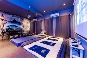 Ein Zimmer mit einem großen Bett, einem Schreibtisch, einem Projektor und Wandgemälde.