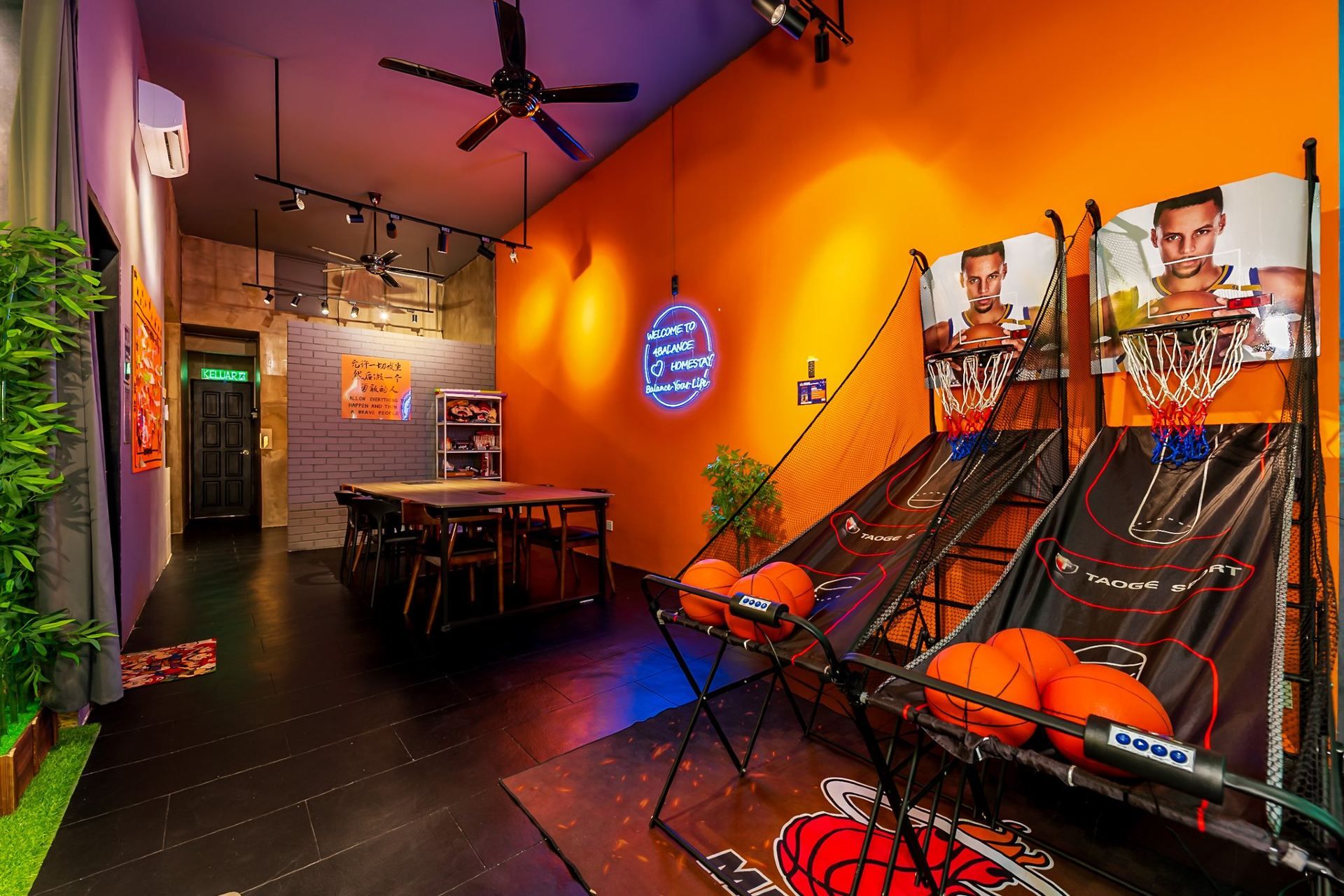A basketball arcade with a neon sign, a basketball hoop, and a seating area with tables and chairs.