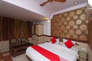 Una habitación de hotel con cama, escritorio, dos sillas, armario y pared con diseño.