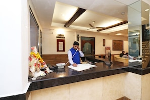 A hotel reception area with a reception desk, a clock, and a framed sign above it. - Hotel O by OYO Highway Inn International (Kolkata)