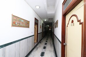 A corridor with doors on both sides, a patterned floor, and a ceiling with recessed lighting.
