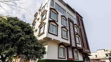 A multi-story building with a white facade, multiple windows, and a green awning.