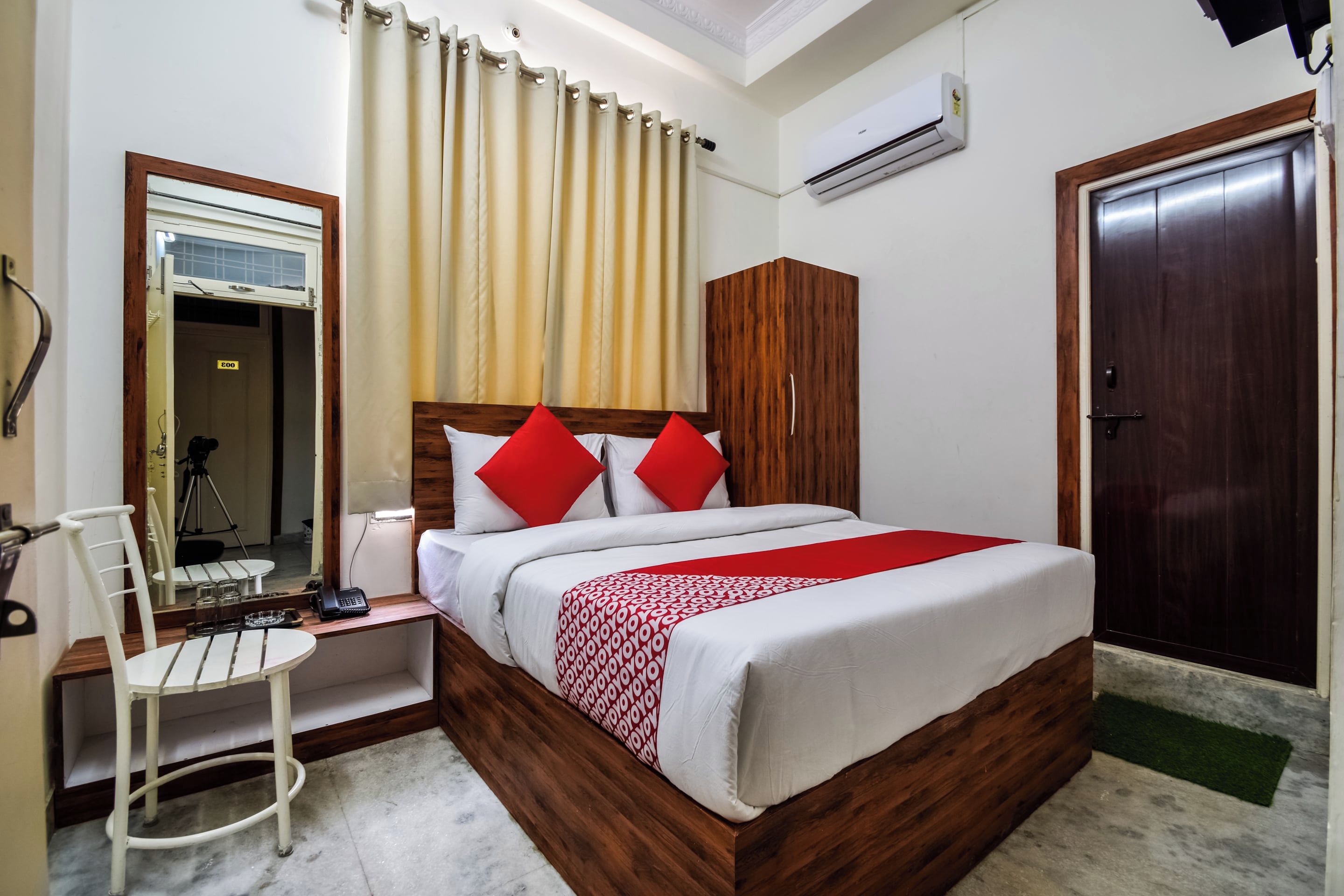 A hotel room with a bed, a desk, a chair, a wardrobe, and a door.
