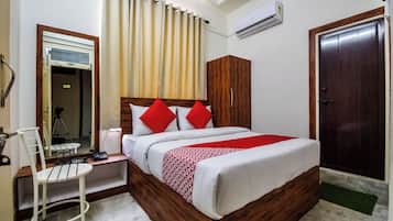 A hotel room with a bed, a desk, a chair, a wardrobe, and a door.