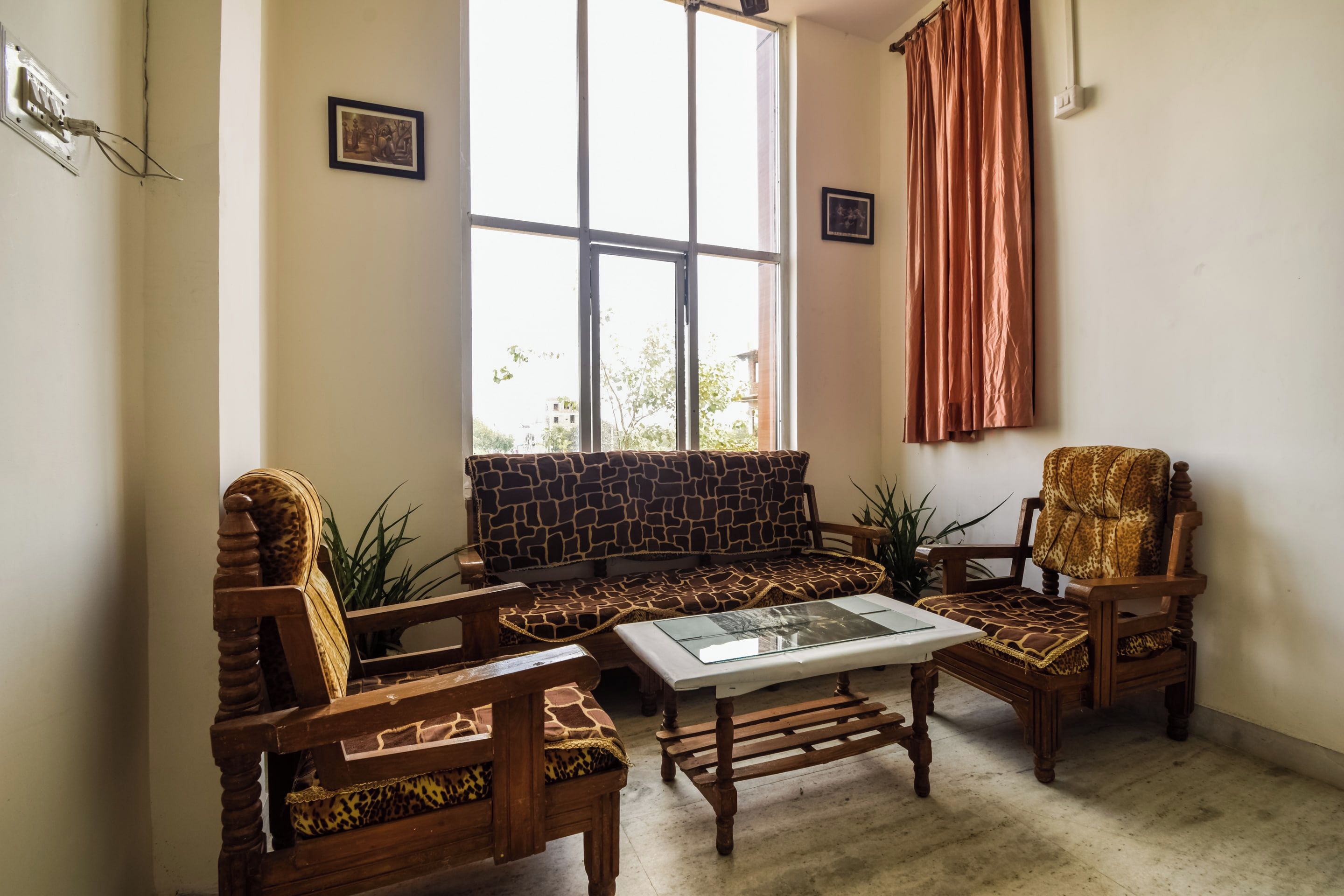 Una sala de estar con un sofá, dos sillones, una mesa de centro y un ventanal con cortinas.