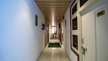 Un pasillo con techo de madera, un felpudo verde al final y una puerta con la etiqueta '305'.
