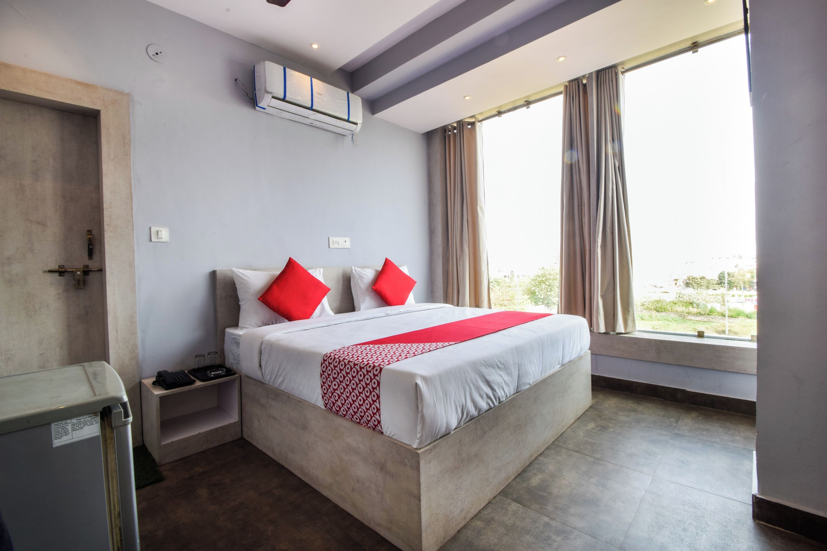 A hotel room with a large bed, a bedside table, a wardrobe, and a window with curtains.