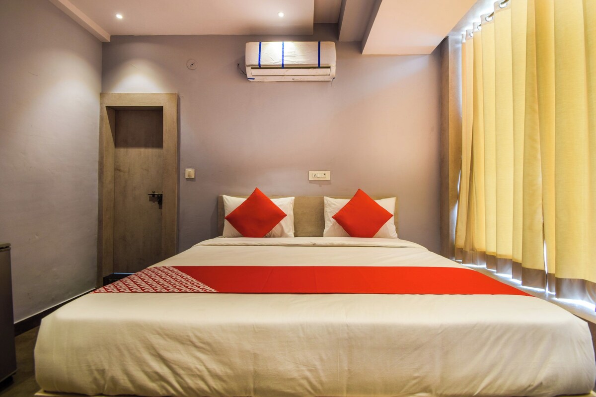 Een hotelkamer met een bed, een deur, een airconditioning en gordijnen.