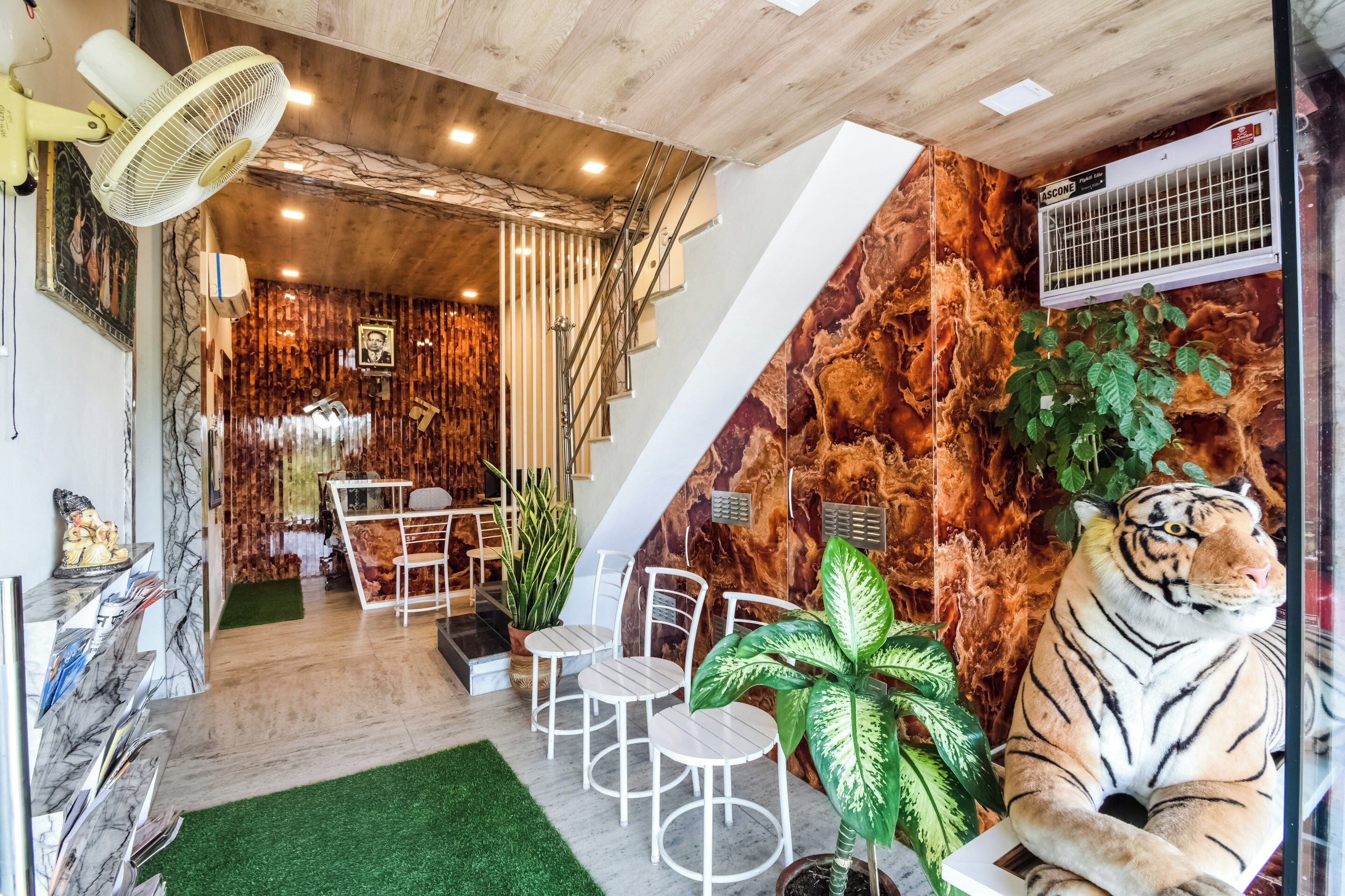 A room with a dining area, a large tiger statue, and a wall with a textured pattern.
