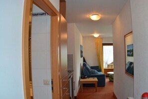 A compact living space with a kitchenette, a sofa, a small table, and a window with curtains. - KLA8 in the Säuling House (Schwangau)