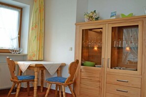 A dining area with a table, chairs, and a cabinet with glass doors. - KLA8 in the Säuling House (Schwangau)