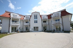 A multi-story building with a central entrance, balconies, and a paved courtyard. - Holiday apartment with 1 bedroom (Kühlungsborn)