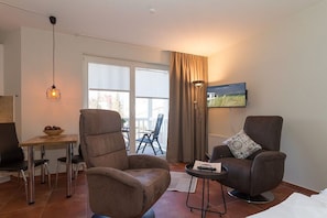 A modern living room with a sofa, armchair, and a small table with a bowl. - Holiday apartment with 1 bedroom (Kühlungsborn)
