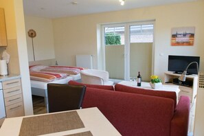 A hotel room with a bed, a sofa, a dining table, a TV, and a window with blinds. - Apartment in Jork with swimming pool (Jork)