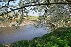 A river with a bridge, surrounded by greenery and a building in the background. - Apartment in Jork with swimming pool (Jork)