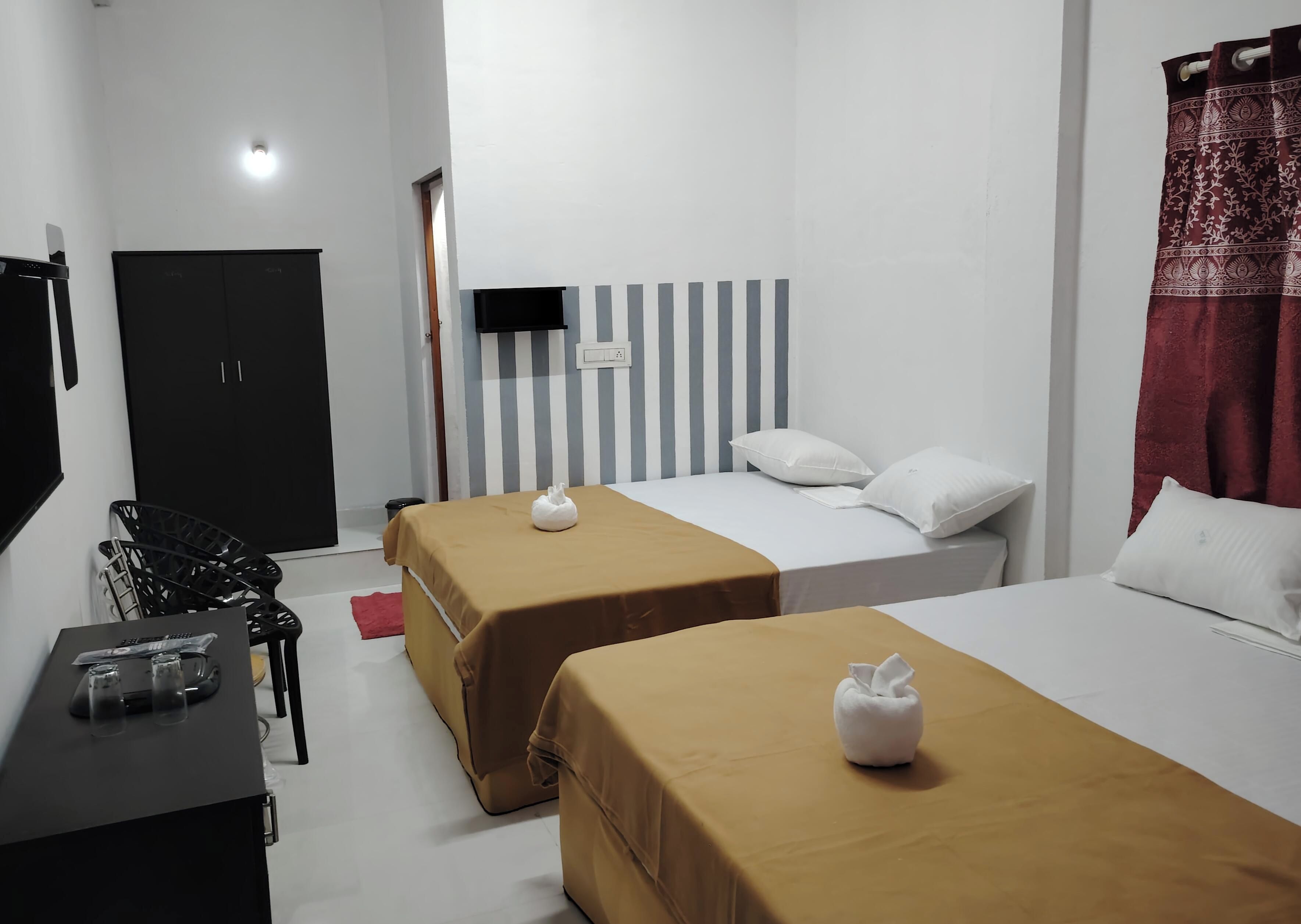 Habitación de hotel con dos camas, un escritorio con vasos, una silla y un televisor.
