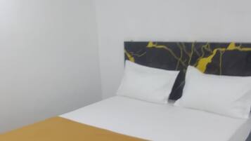 A bed with a white mattress and a mustard-colored bedspread.