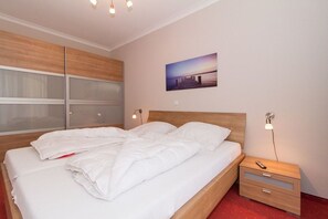 A hotel room with a large bed, a nightstand with a lamp, and a wall-mounted picture. - Holiday apartment with 1 bedroom (Kühlungsborn)