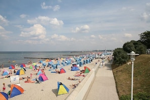 A beach with numerous colorful tents and umbrellas, a walkway, and a pier in the background. - Holiday apartment with 1 bedroom (Kühlungsborn)
