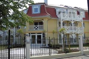 A two-story building with a red-tiled roof, white balconies, and a gated entrance. - Holiday apartment with 1 bedroom (Kühlungsborn)