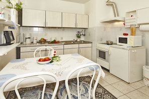 A kitchen with white cabinets, a microwave, a stove, and a dining table with chairs. - Holiday apartment with 1 bedroom (Ahlbeck)