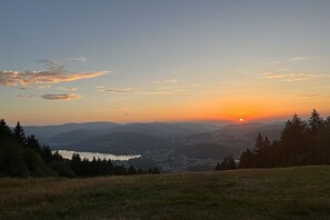 Ein Sonnenuntergang über einem Tal mit einem See und einer Stadt in der Ferne.