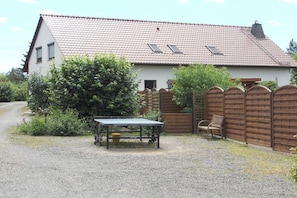 A house with a gravel driveway, a wooden fence, and a table with chairs outside. - Holiday home with 1 bedroom (Schwielochsee)
