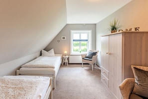 A bedroom with two beds, a chair, a small table, and a wardrobe. - Holiday apartment with 2 bedrooms (Midlum)